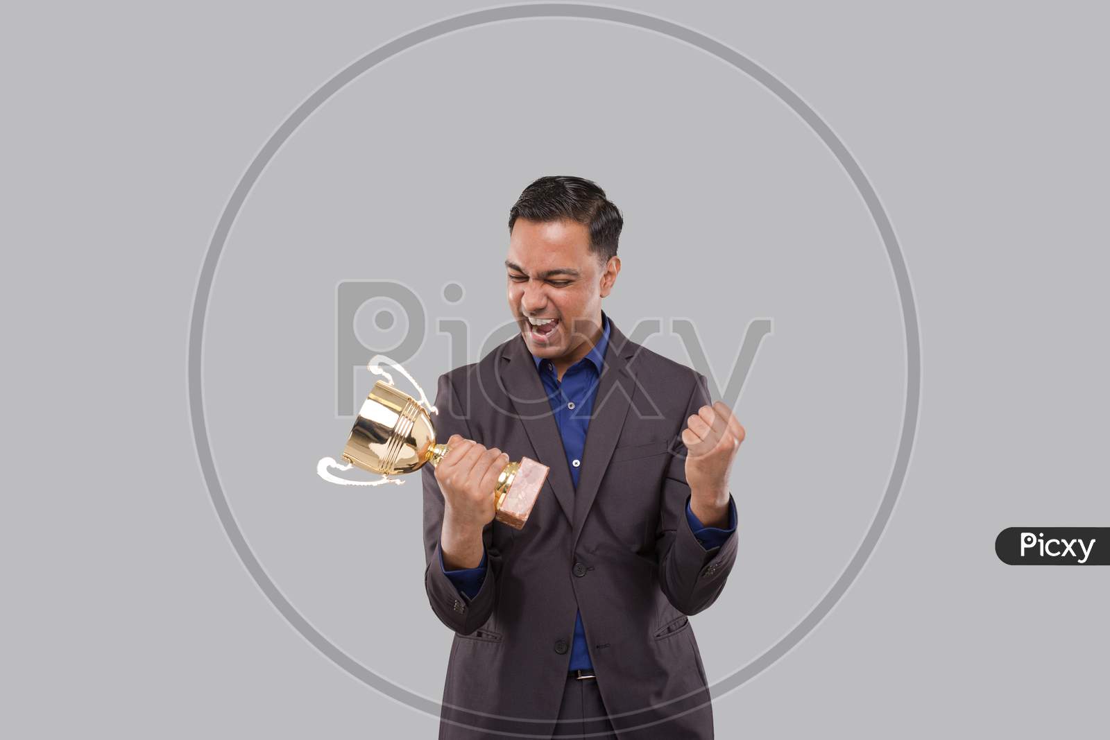 Businessman Very Happy And Excited, Raising Arms, Celebrating A Victory Or Success Holding Trophy. Winner Sign. Indian Business Man Isolated With Trophy In Hands