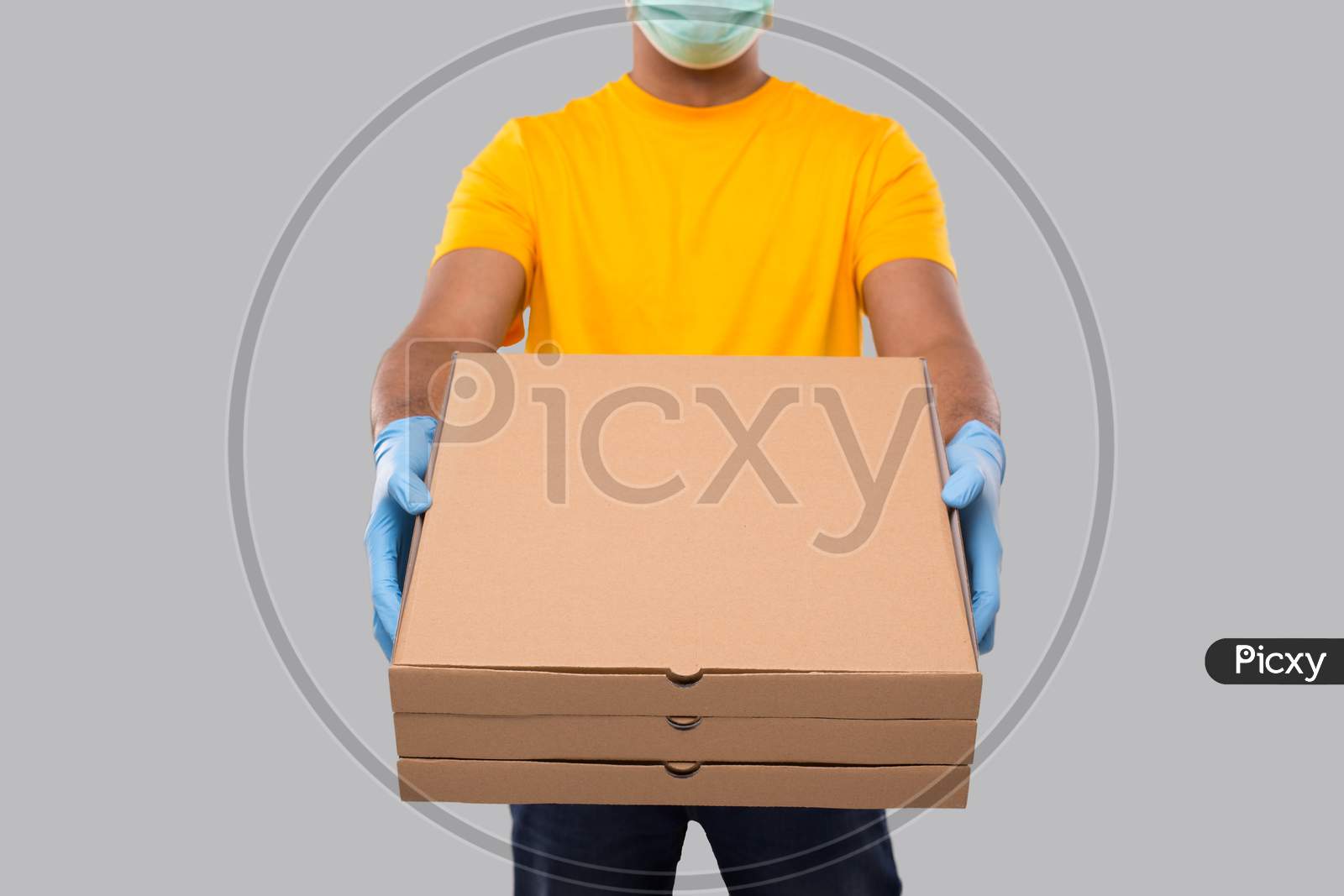 Delivery Man Three Pizza Box In Hands Wearing Medical Mask And Gloves Close Up Isolated. Yellow Tshirt Indian Delivery Boy. Man With Pizza In Hands