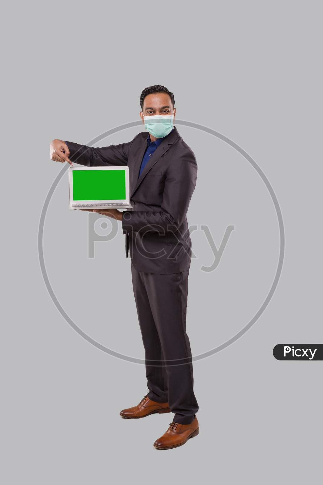 Businessman Pointing At Laptop Green Screen Isolated Wearing Medical Mask And Gloves. Indian Business Man With Laptop In Hands. Online Business Concept