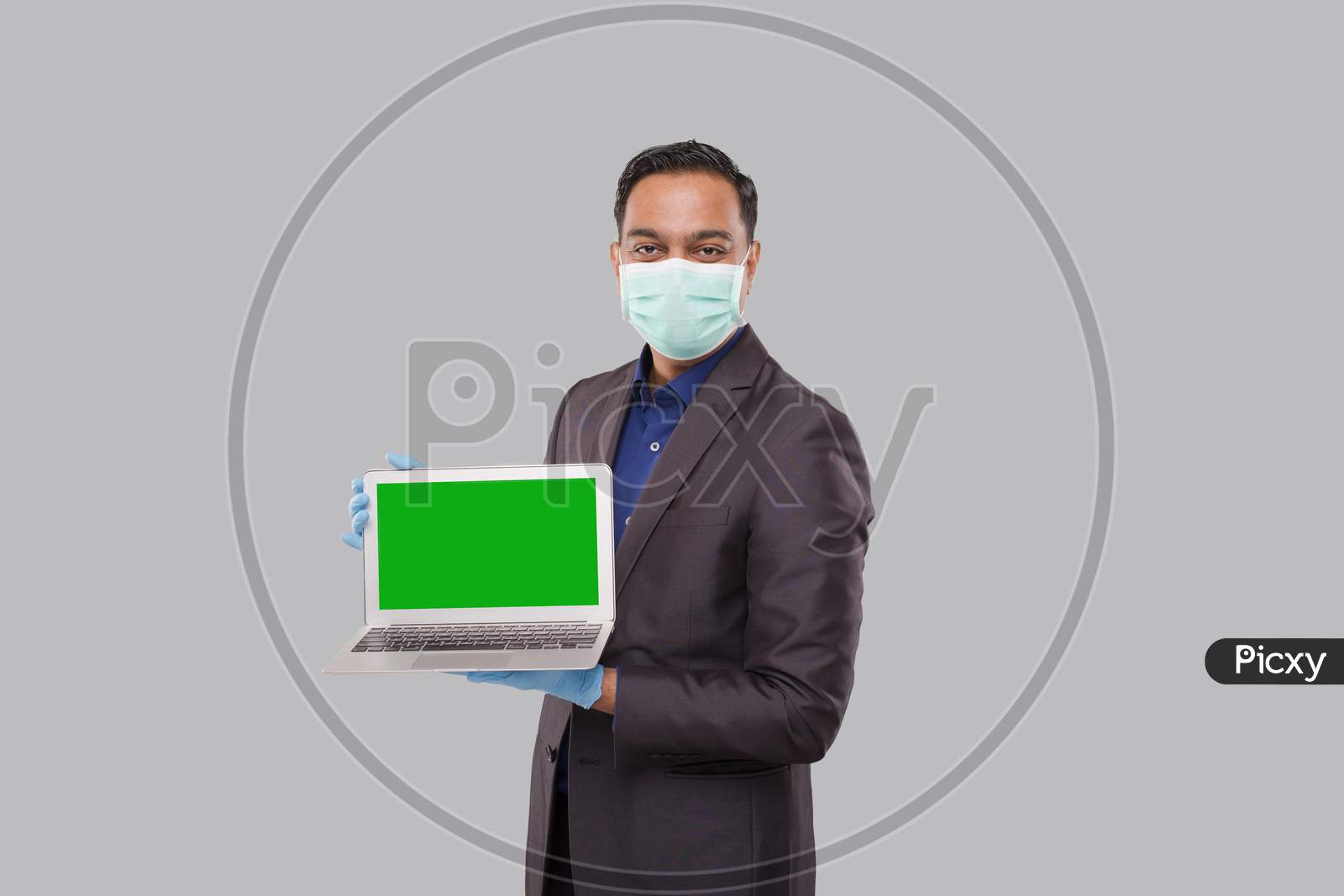 Businessman Showing Laptop Green Screen Wearing Medical Mask And Gloves Isolated. Indian Business Man With Laptop In Hands. Online Business Concept