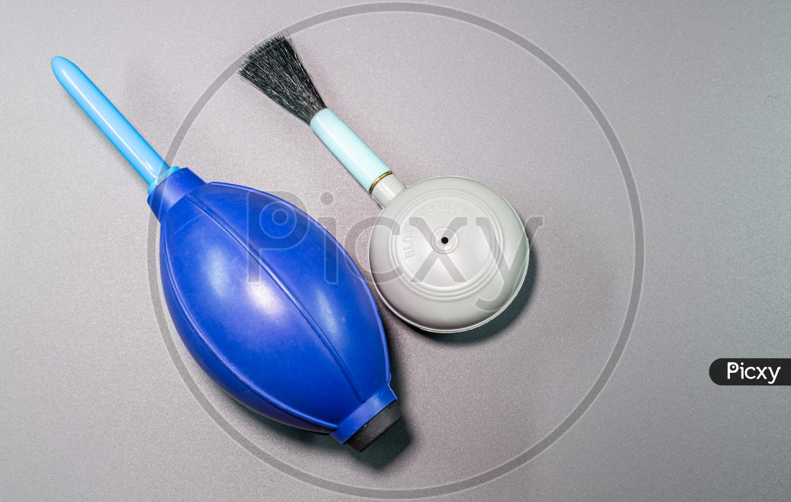 An Isolated View Of Hand Blower Brush And Blower In A Gray Background
