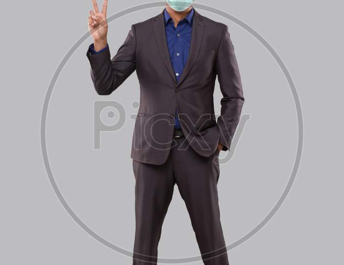 Businessman Showing Peace Sign Wearing Medical Mask. Indian Businessman Standing Full Length.