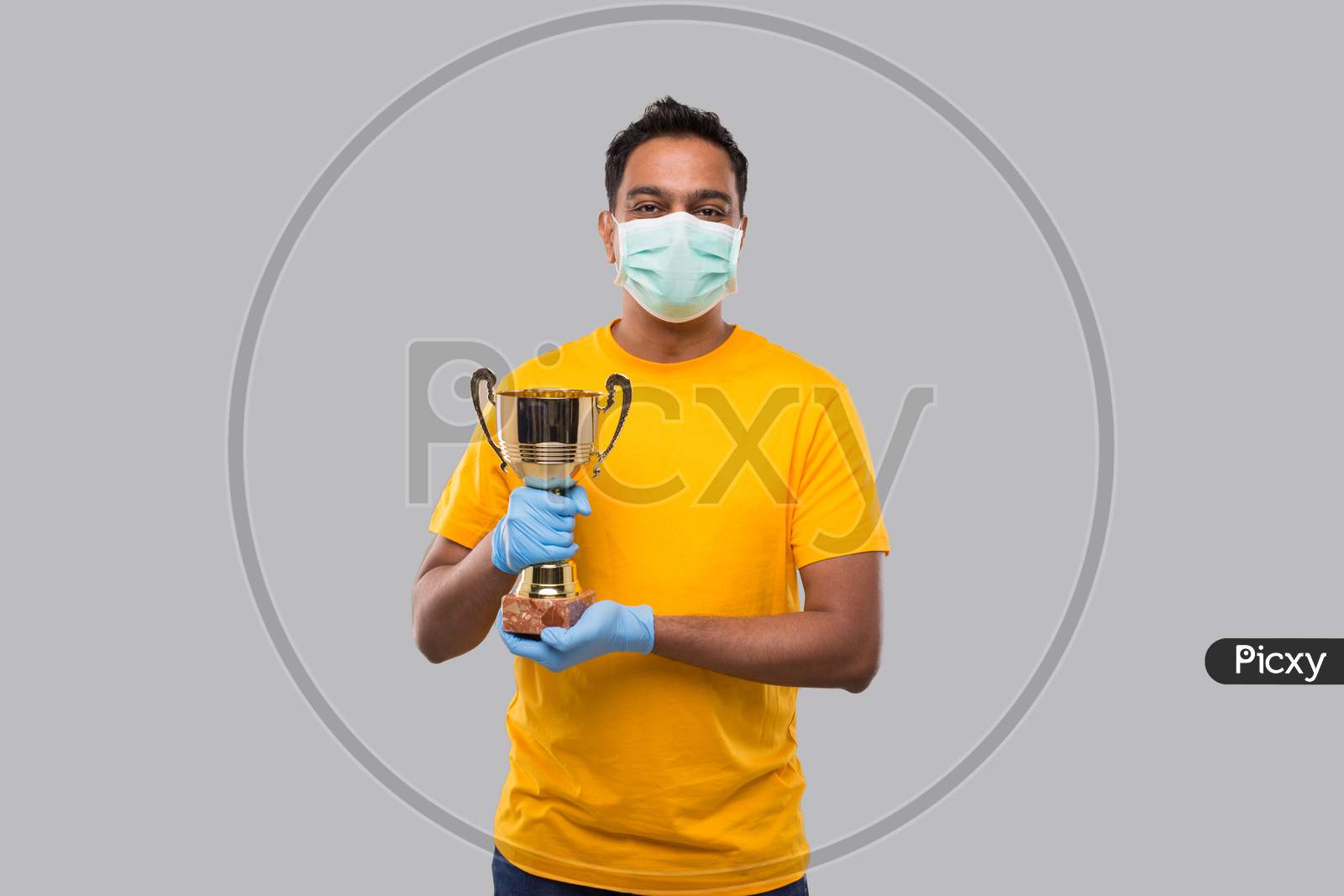 Indian Man Holding Trophy In Hands Wearing Medical Mask And Gloves Isolated