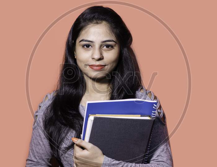 Smiling Indian female student holding books and file , college or school student and education concept.