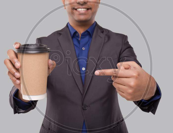 Businessman Pointing At Coffee To Go Cup Isolated Close Up. Indian Business Man With Coffee Take Away Cup In Hands