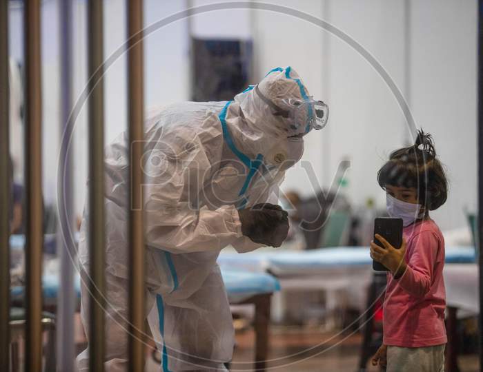 A health worker wearing a PPE kit interacts with a child at the Common Wealth Games Stadium which has been temporarily converted into a Coronavirus Care Centre in New Delhi on July 17, 2020