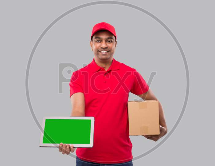 Indian Delivery Man Holding Tablet And Carpet Box. Delivery Boy Smilling Isolated