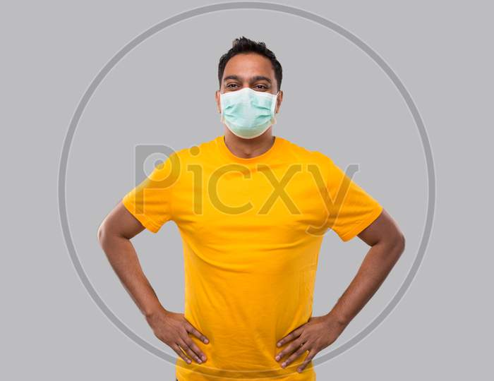 Indian Man Hands To Sides Wearing Medical Mask In Yellow Tshirt Isolated