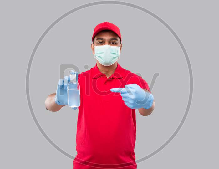 Delivery Man Ponting At Hands Sanitizer Wearing Medical Mask And Gloves Isolated. Indian Delivery Boy Holding Hand Antiseptic