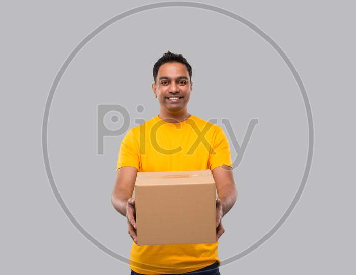 Indian Man With Box In Hands Isolated. Yellow Tshirt Delivery Boy. Home Delivery. Quarantine Hero. Man Smiling