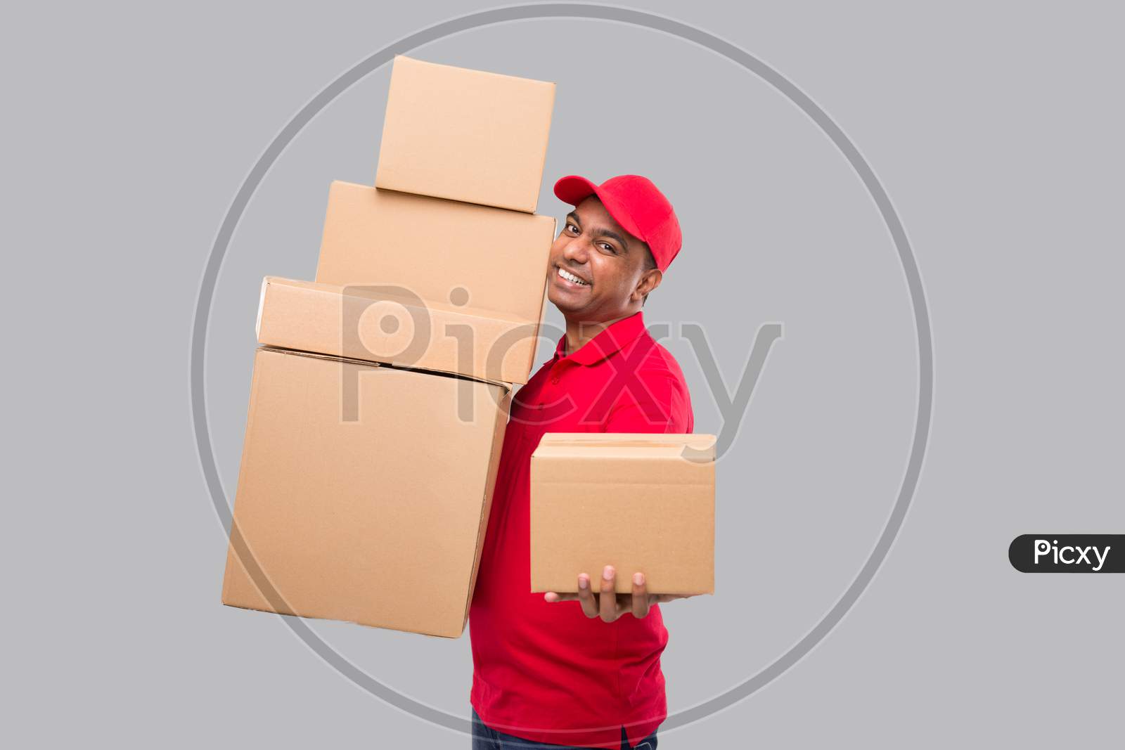 Delivery Man Holding A Lot Carton Boxes Isolated. Indian Delivery Boy Overloaded With Boxes. Gives Out Box To Client