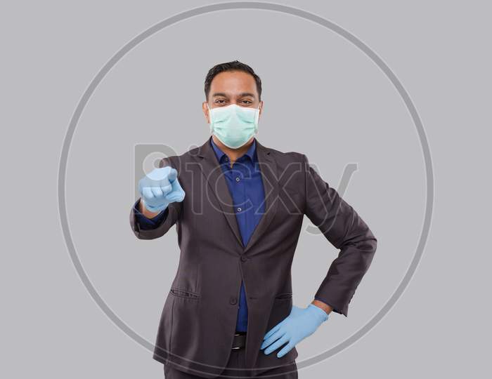 Businessman Pointing Front Watching In Camera Wearing Medical Mask And Gloves Isolated. Indian Business Man Pointing Front