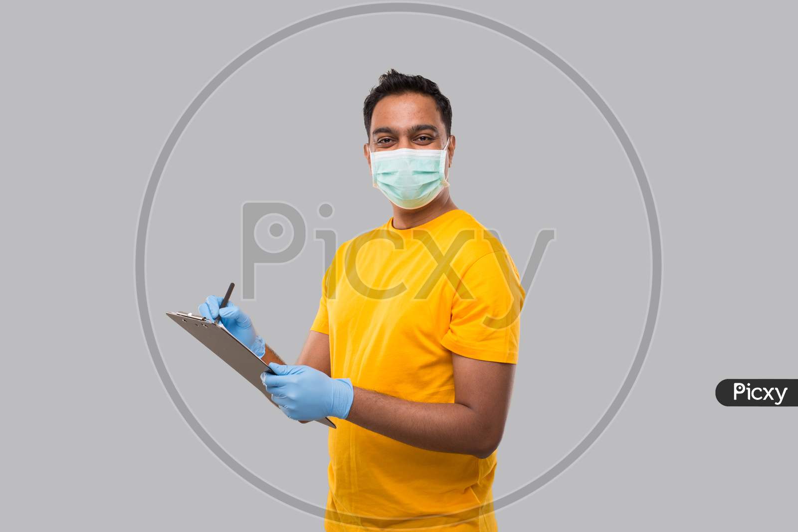 Indian Man Writing In Clipboard Wearing Medical Mask And Gloves Watching In Camera. Indian Man Clipboard