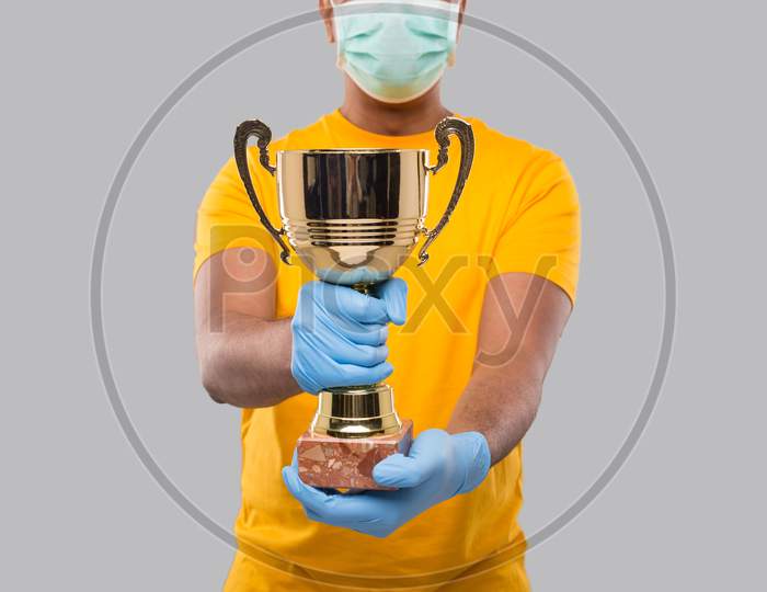 Indian Man Holding Trophy In Hands Wearing Medical Mask And Gloves Close Up Isolated
