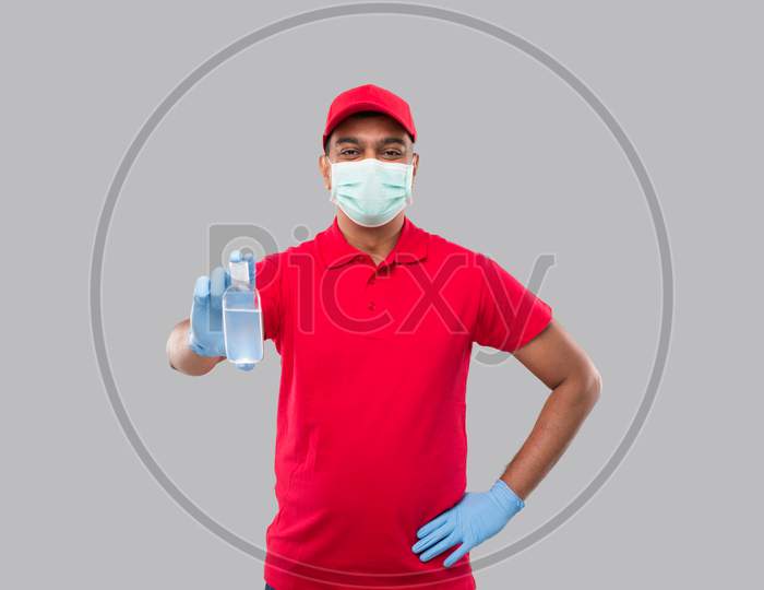 Delivery Man Showing Hands Sanitizer Wearing Medical Mask And Gloves Isolated. Indian Delivery Boy Holding Hand Antiseptic