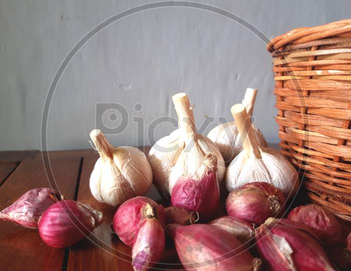 Garlic and onion are scattered on a wooden board