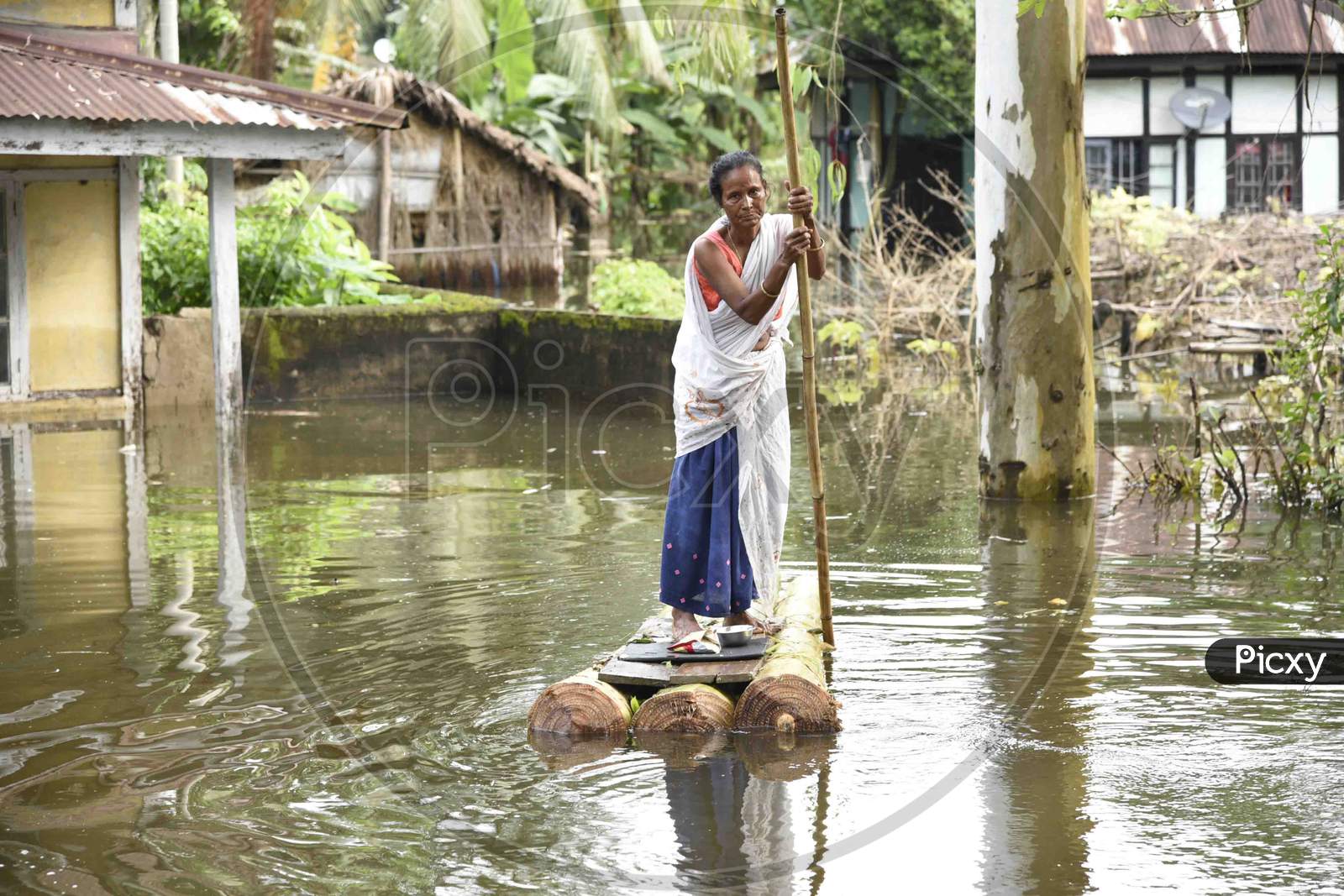 A woman cross a flooded area on makeshift banana raft