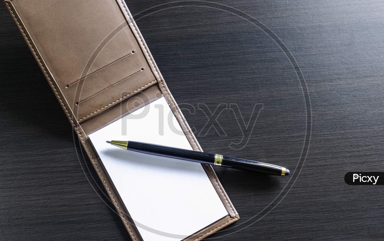 A Pen And Small Daily Note On A Black Table