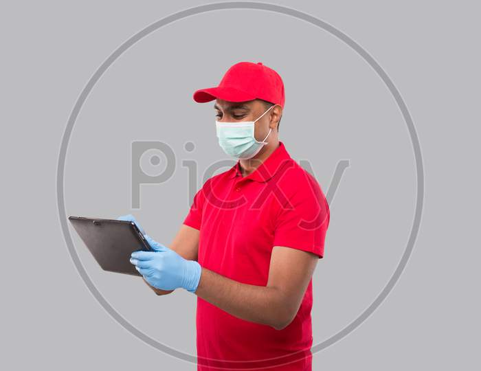 Delivery Man Using Tablet Wearing Medical Mask And Gloves. Indian Delivery Boy With Tablet In Hands. Home Delivery, Technical Delivery