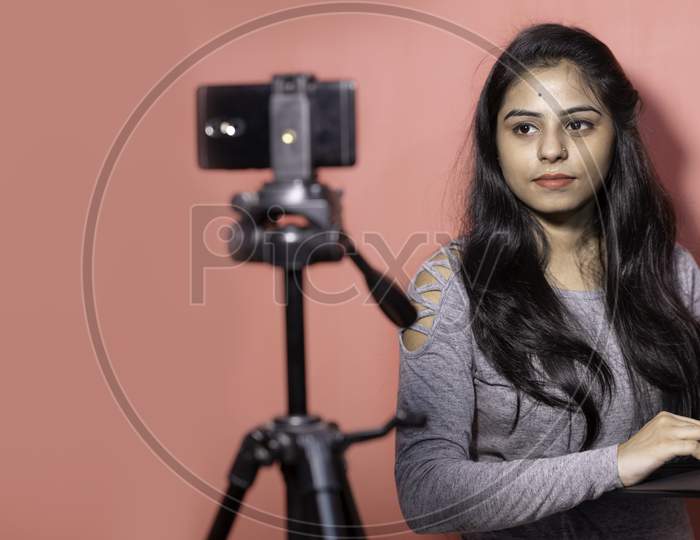 A young woman taking virtual online classes on smartphone and laptop. Concept of e-teaching, virtual online video classes, self isolated quarantine lifestyle and education in India.