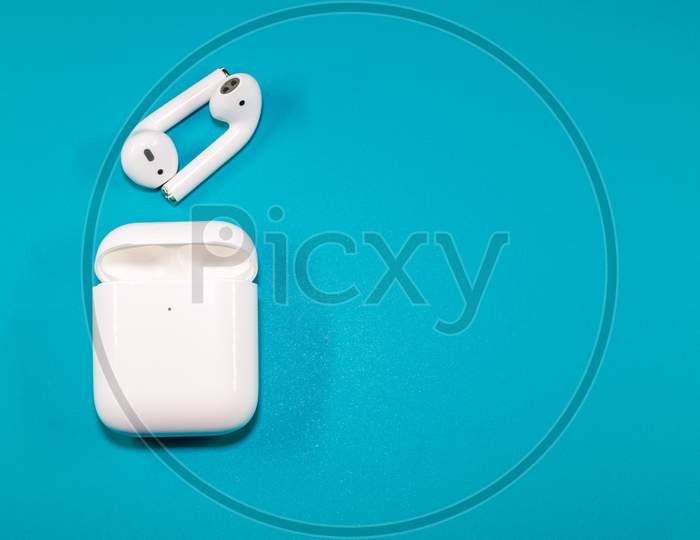 An Isolated View Of A Wireless Earpods And Charging Case In A Blue Background
