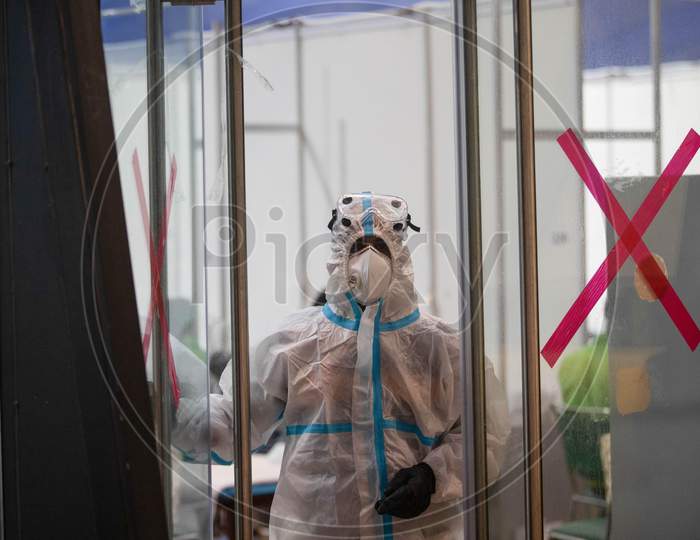 A health worker wearing a PPE suit looks through the glass at the Common Wealth Games stadium which has been converted into a Coronavirus Care Centre in New Delhi on July 17, 2020