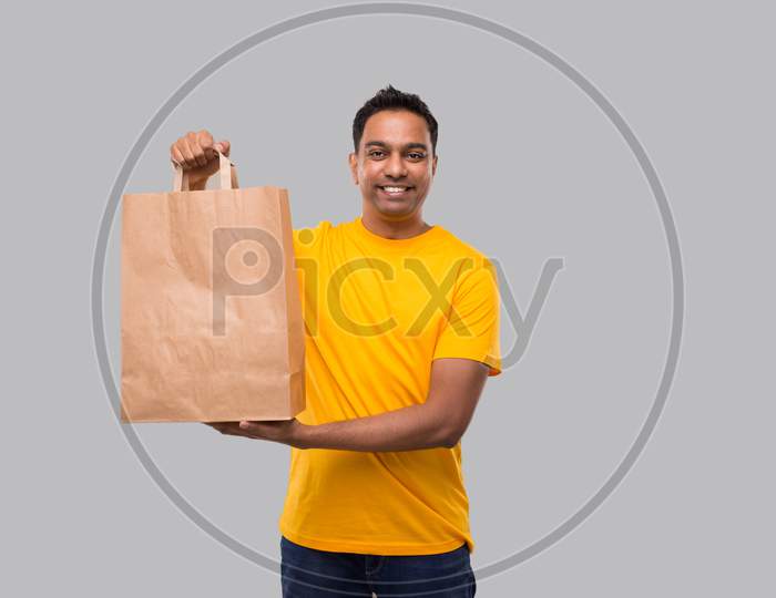 Indian Man With Paper Bag In Hands Isolated. Yellow Uniform Indian Delivery Boy. Home Food Delivery. Paper Bag