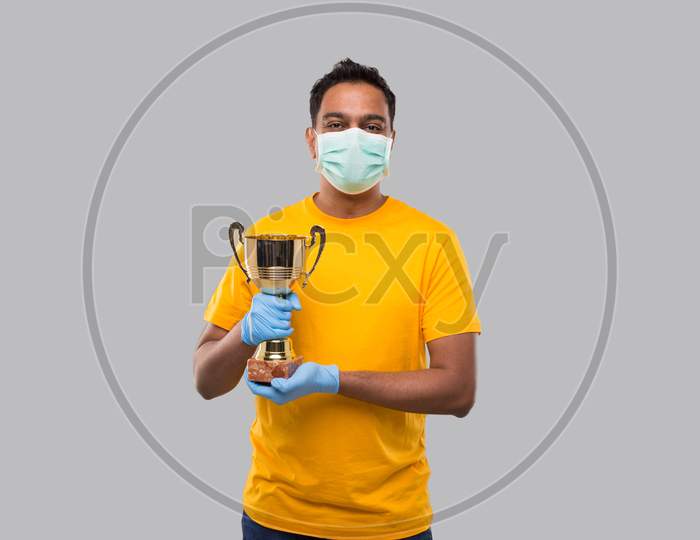Indian Man Holding Trophy In Hands Wearing Medical Mask And Gloves Isolated