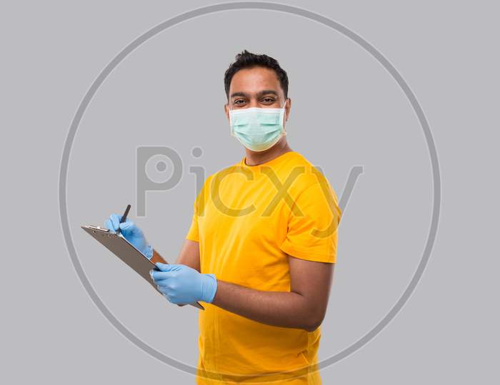Indian Man Writing In Clipboard Wearing Medical Mask And Gloves Watching In Camera. Indian Man Clipboard
