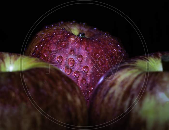 A Fresh Red Apple In Spot Light With Reflecting Water Drops On It, Blurry Black Background, Long Exposure Photography