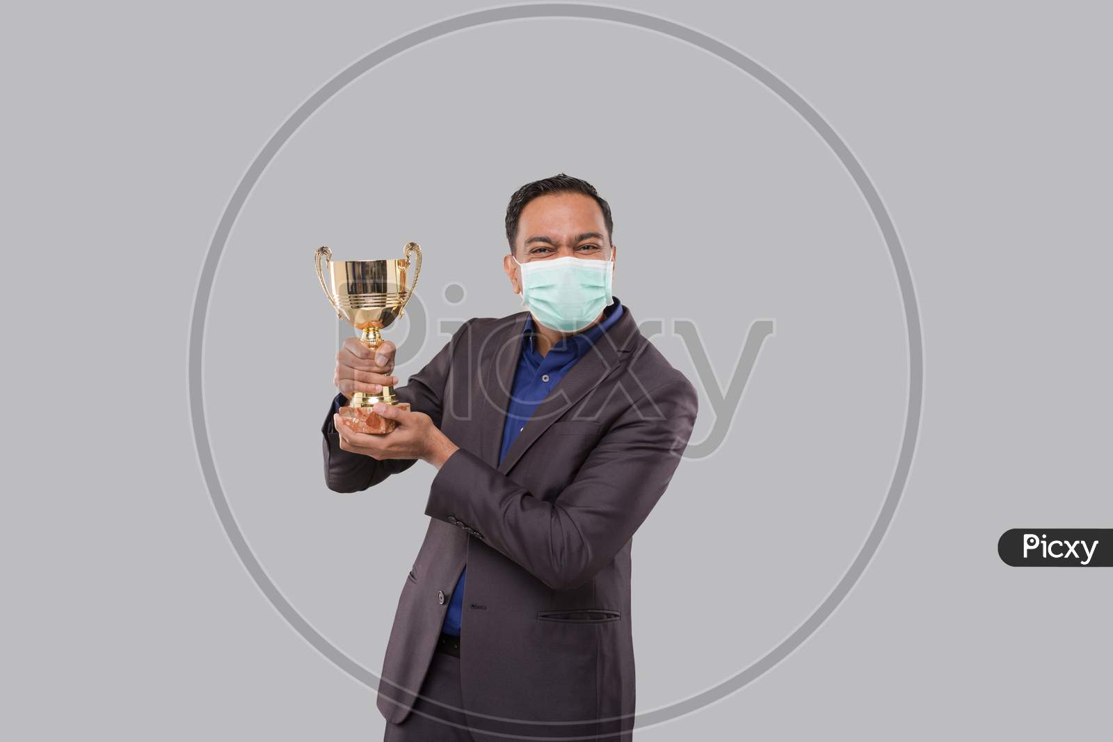 Businessman Holding Trophy Wearing Medical Mask. Indian Business Man Standing With Trophy In Hands