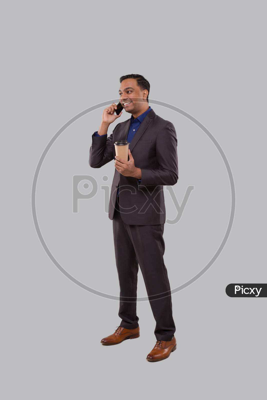 Businessman Talking On Phone With Coffee To Go Cup Isolated. Indian Business Man With Coffee Take Away Cup Standing Full Length