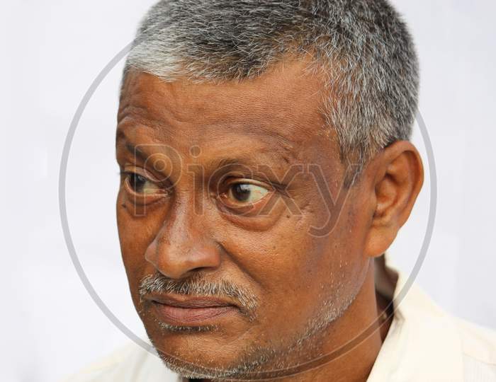 Angry senior Indian man face portrait on white background. Old man looking side way.