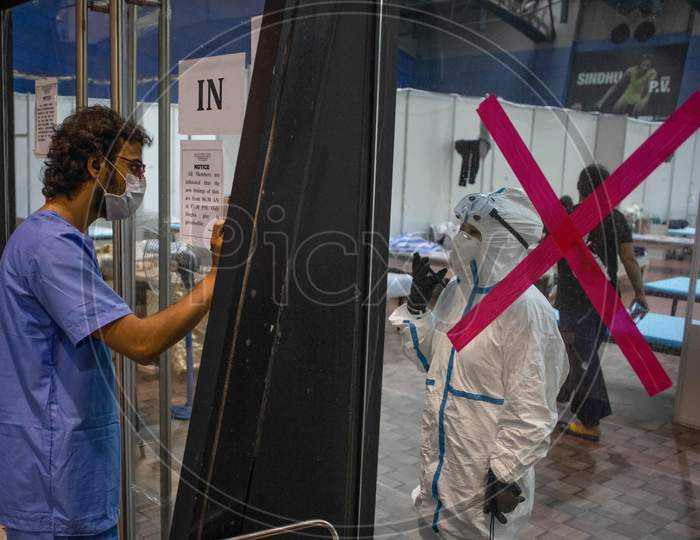 A health worker wearing a PPE kit interacts with a patient at the Common Wealth Games Stadium through a glass door which has been temporarily converted into a Coronavirus Care Centre in New Delhi on July 17, 2020