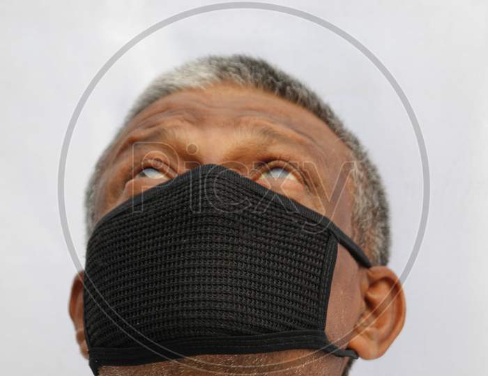 Black protection mask closeup wearing by senior Indian man on white background.