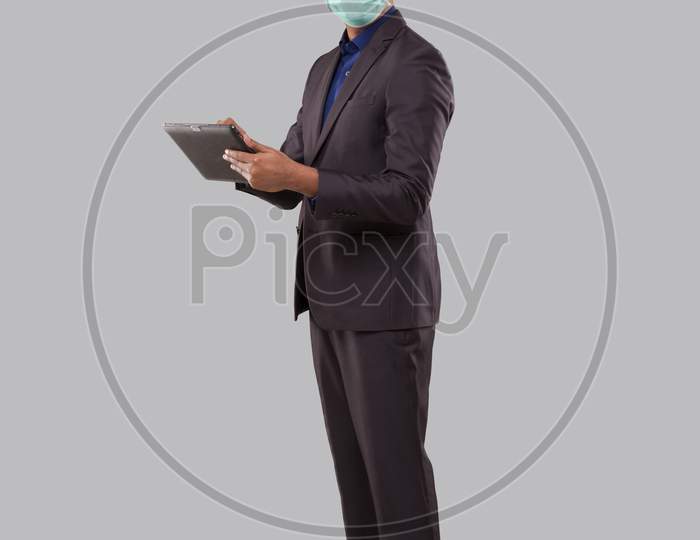 Businessman Using Tablet Wearing Medical Mask Isolated. Indian Business Man Standing Full Length With Tablet In Hands