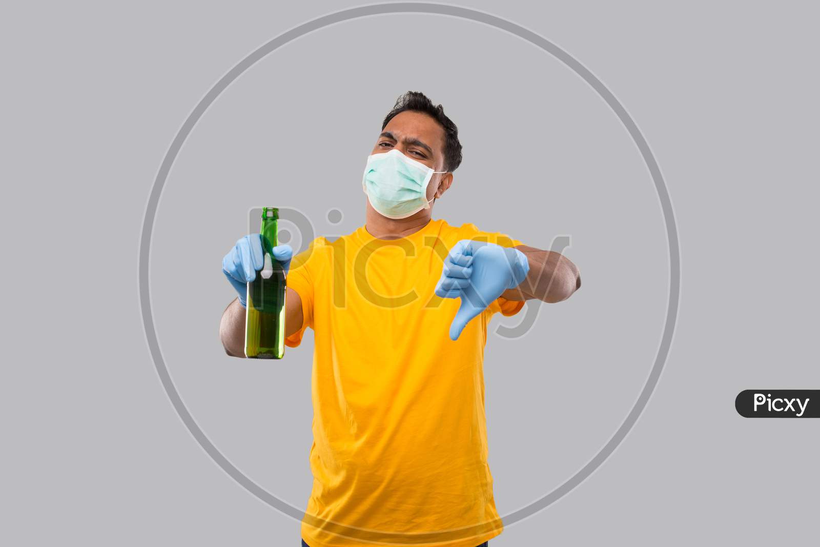 Indian Man Holding Beer Bottle Showing Thumb Down Wearing Medical Mask And Gloves Isolated.