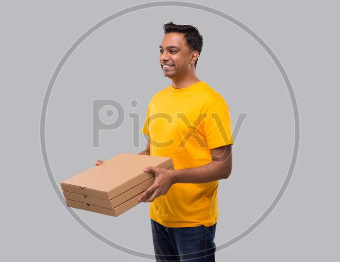 Man Three Pizza Box In Hands Watching Side Isolated. Yellow Tshirt Indian Delivery Boy. Man With Pizza In Hands