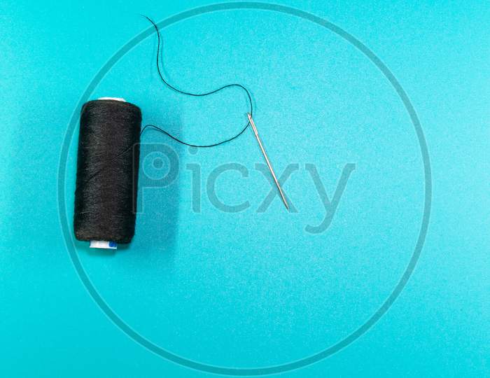 Sewing Thread And Needle In A Gray Background