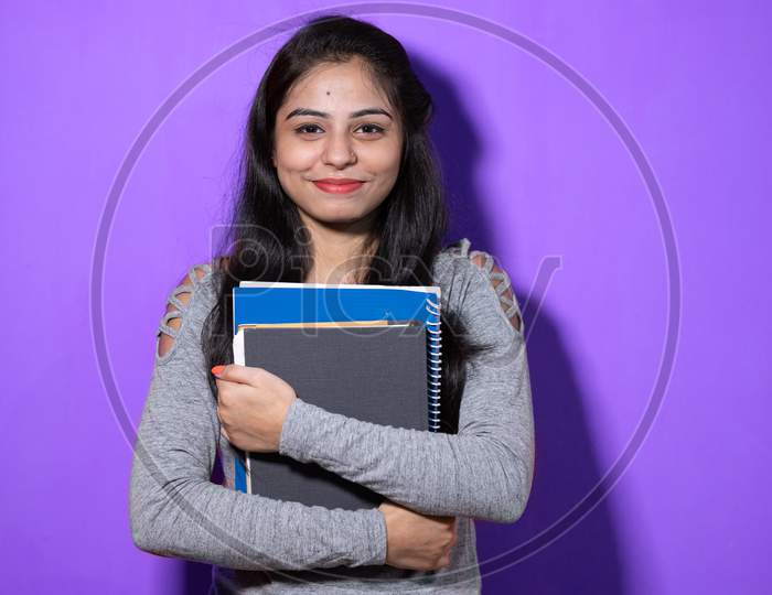 Smiling Indian female student holding books and file , college or school student and education concept isolated on color background with copy space.