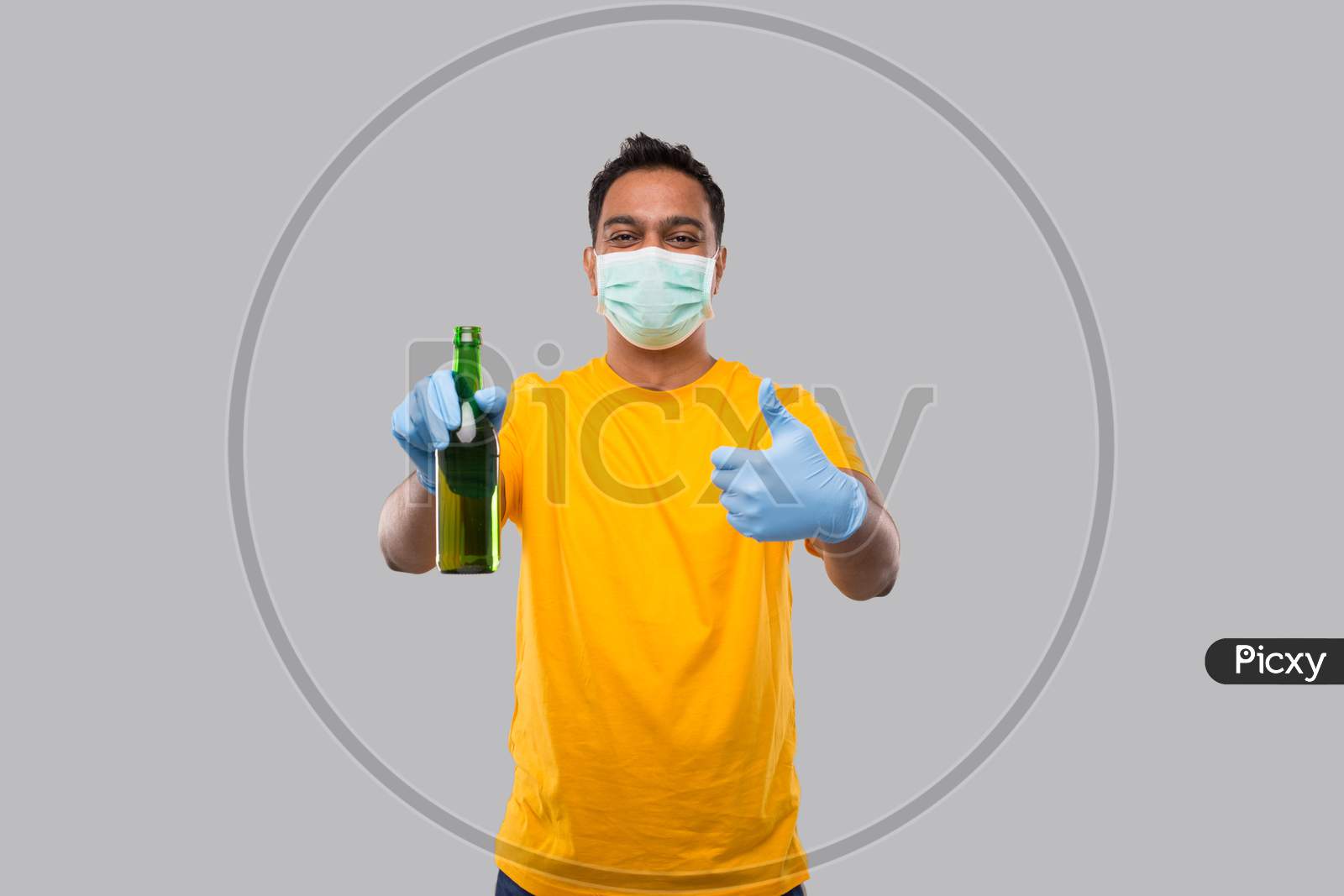 Indian Man Holding Beer Bottle Showing Thumb Up Wearing Medical Mask And Gloves Isolated.