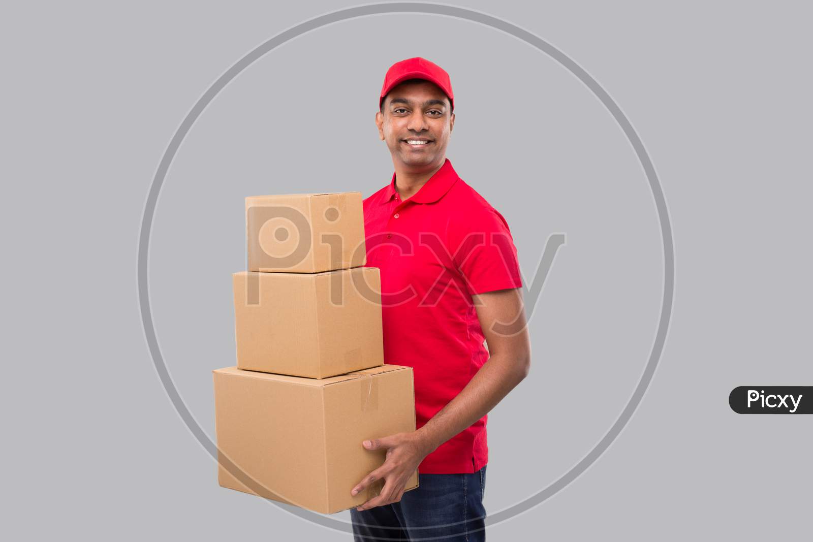 Delivery Man Holding Carton Boxes Isolated. Indian Delivery Boy Smiling With Boxes In Hands