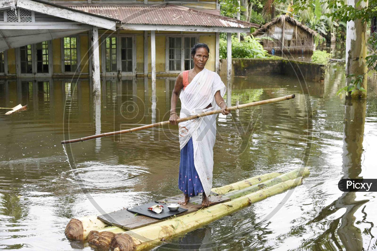 A woman cross a flooded area on makeshift banana raft