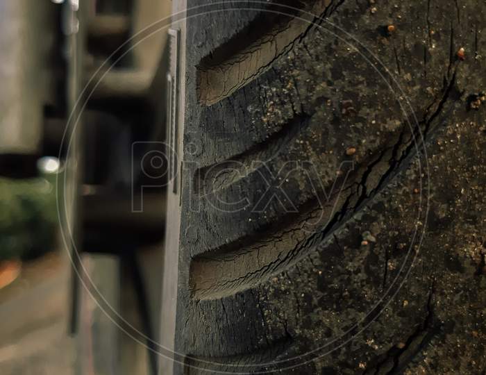 Tyre with some cracks and dirt on it.