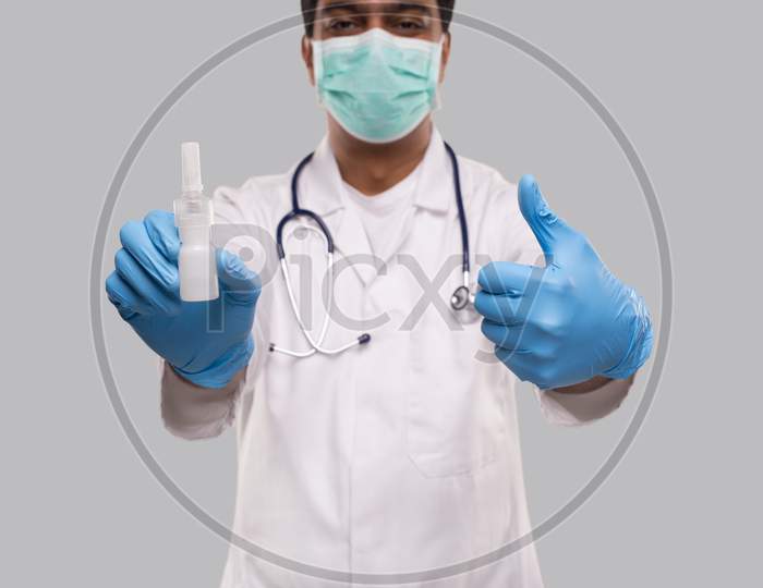 Doctor Showing Nose Spray And Thumb Up Wearing Medical Mask And Gloves Close Up. Indian Man Doctor Nasal Spray. Corona Virus Concept. Isolated