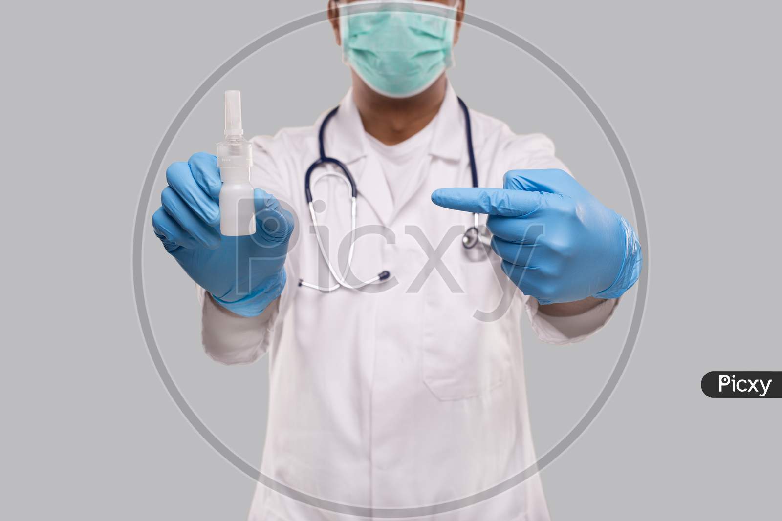 Doctor Pointing At Nose Spray Wearing Medical Mask And Gloves Close Up. Indian Man Doctor Nasal Spray. Corona Virus Concept. Isolated