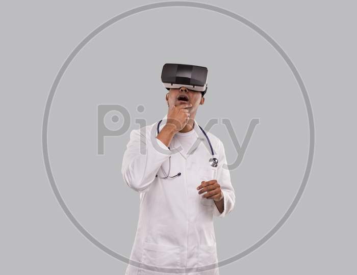 Doctor Excited Wearing Vr Glasses Thinking Isolated. Indian Man Doctor In Virtual Reality