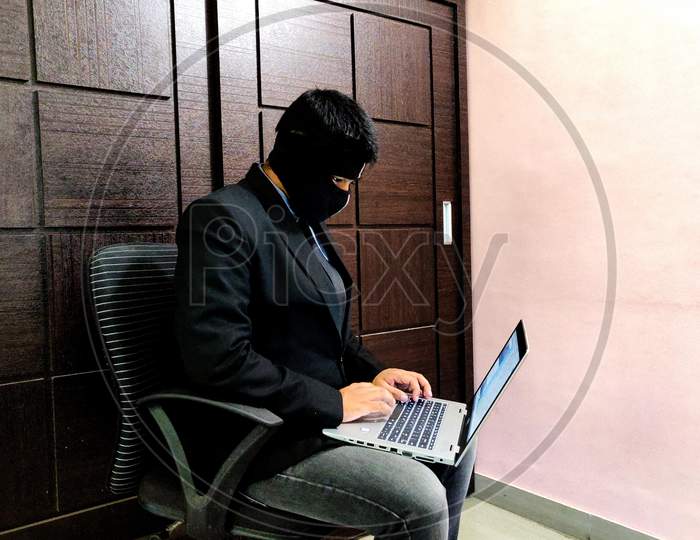 A young man wearing mask and is working on a laptop