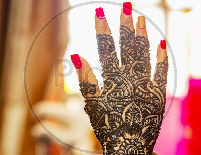 Bride's hand with henna design on wedding eve.