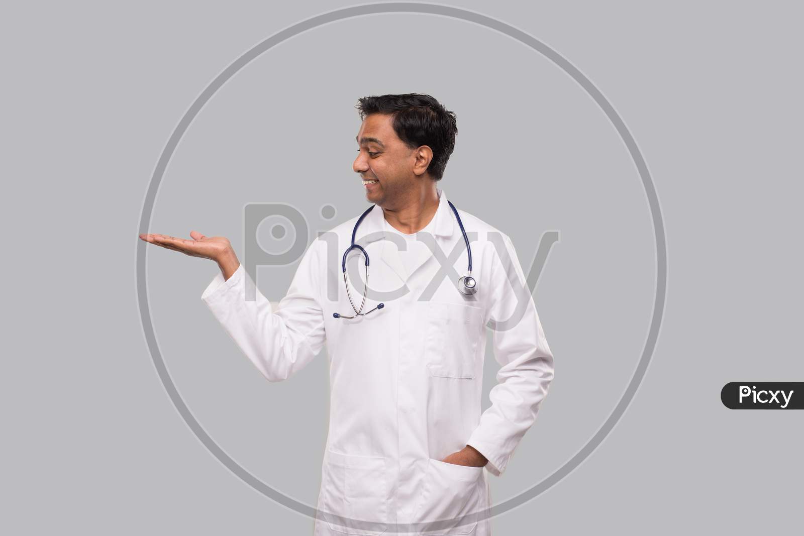 Doctor Holding Hand To Side Watching To Side Isolated. Indian Man Doctor Sign